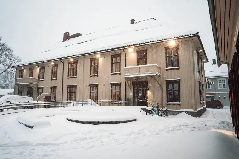Fredheim skole i Kongsberg sentrum, bygget i 1816, med snø og lys i vinduene.