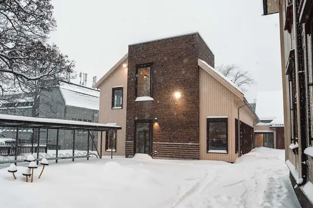 Det nye bygget i mørk tegl ved siden av de gamle bygningene.
