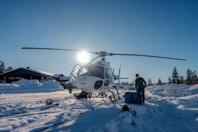 Helikopter på snøen ved hytta.