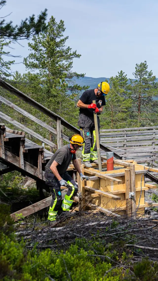 Fagarbeider støper fundament i den bratte skråningen.