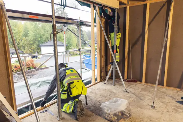 Tømrer i arbeid innvendig, med nye vinduer.